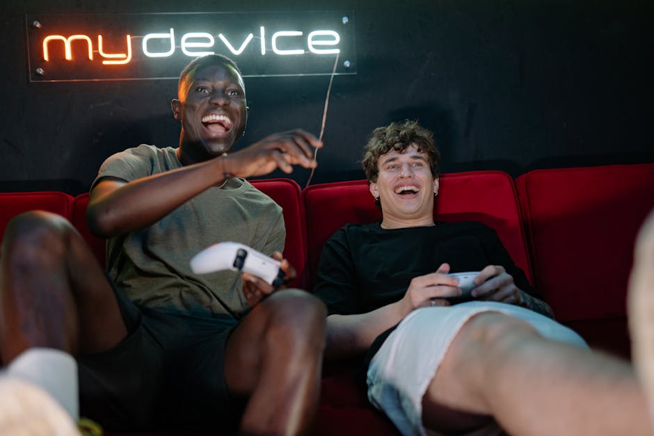 Two friends having fun playing video games, laughing and relaxing on a couch with a neon sign in the background.