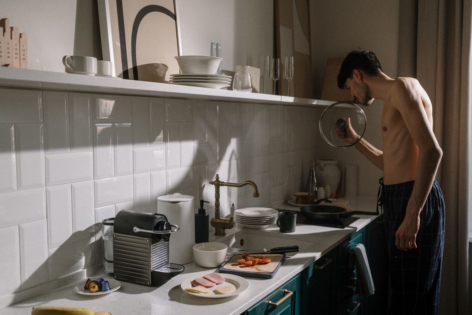 A young man prepares breakfast in a chic kitchen, illustrating a relaxed morning routine.