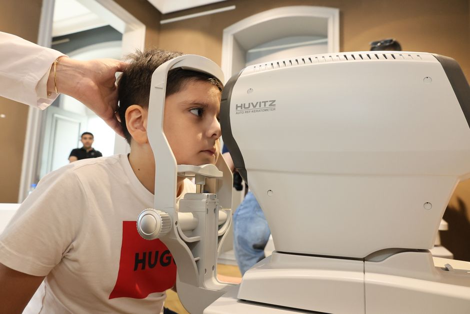 Young boy receiving an eye exam using autorefractor at a clinic. Healthcare concept.