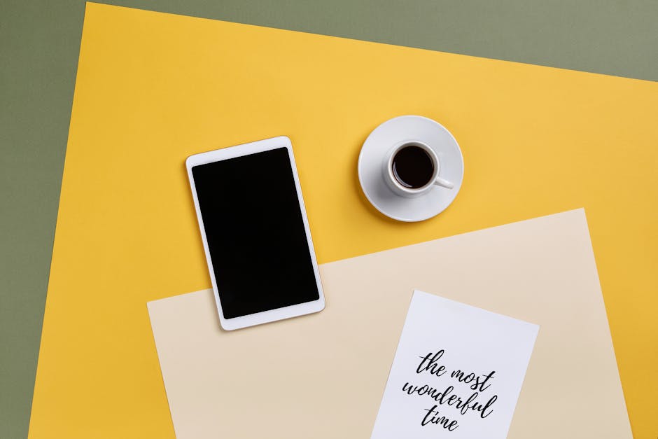A top view of a minimalist office setup with a tablet, coffee, and paper.