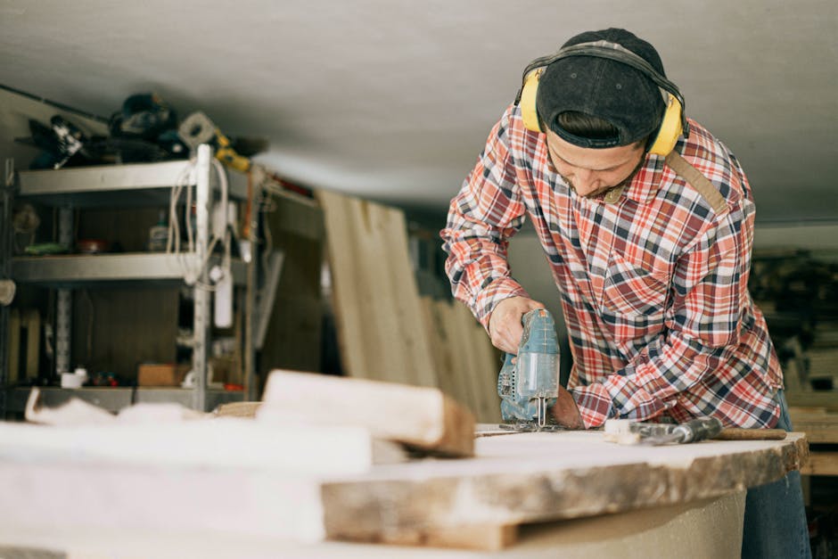 A skilled carpenter uses a power drill in a well-organized woodworking workshop.